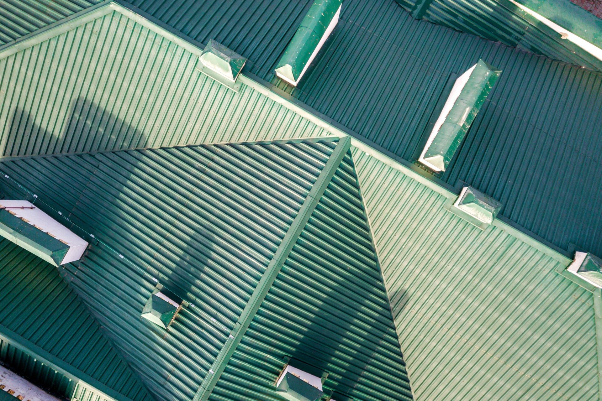 Top aerial view of building green shingle tiled roof with complex configuration construction